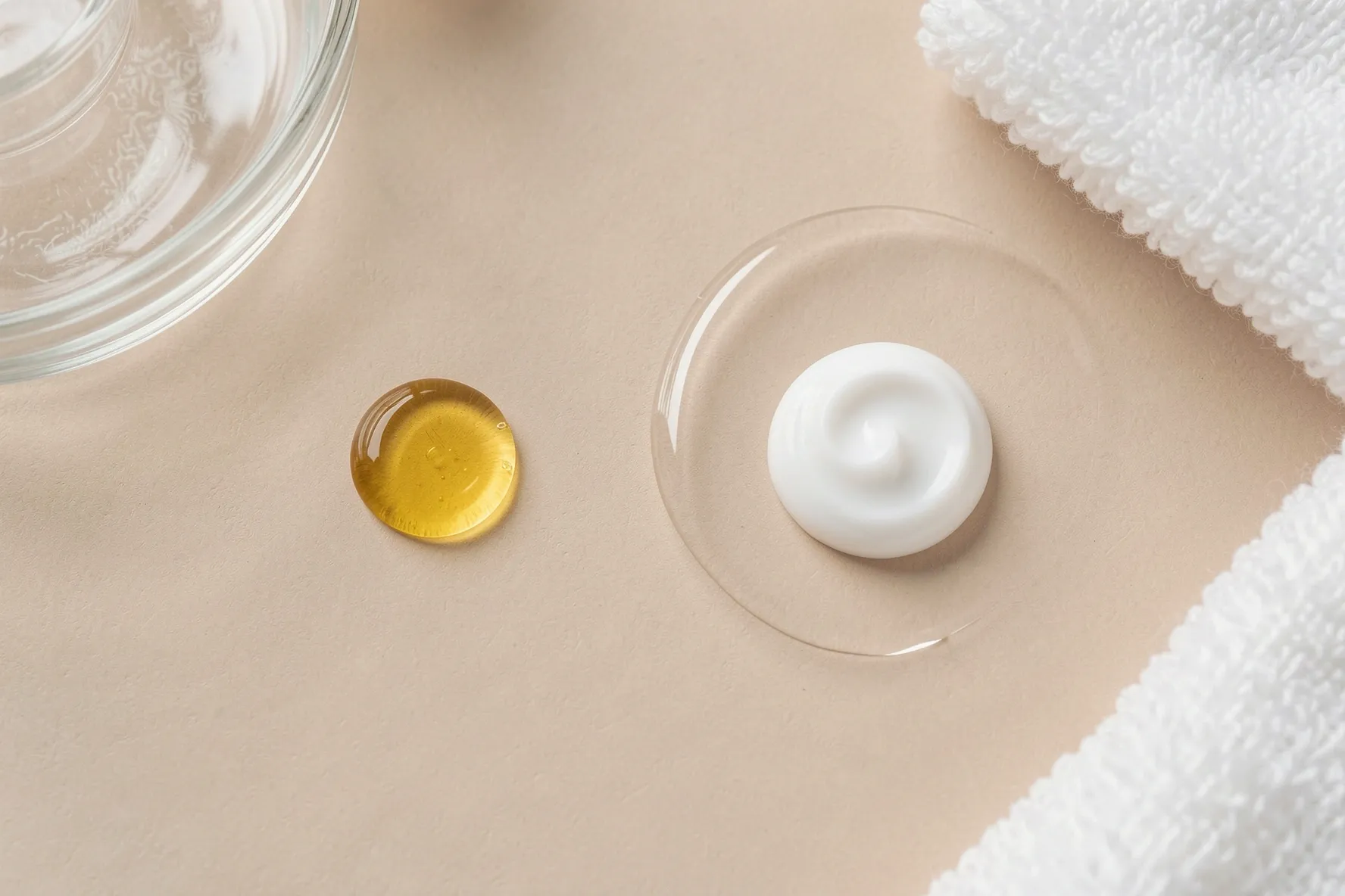 Comparación de textura entre una gota de aceite corporal y una pequeña cantidad de crema hidratante.