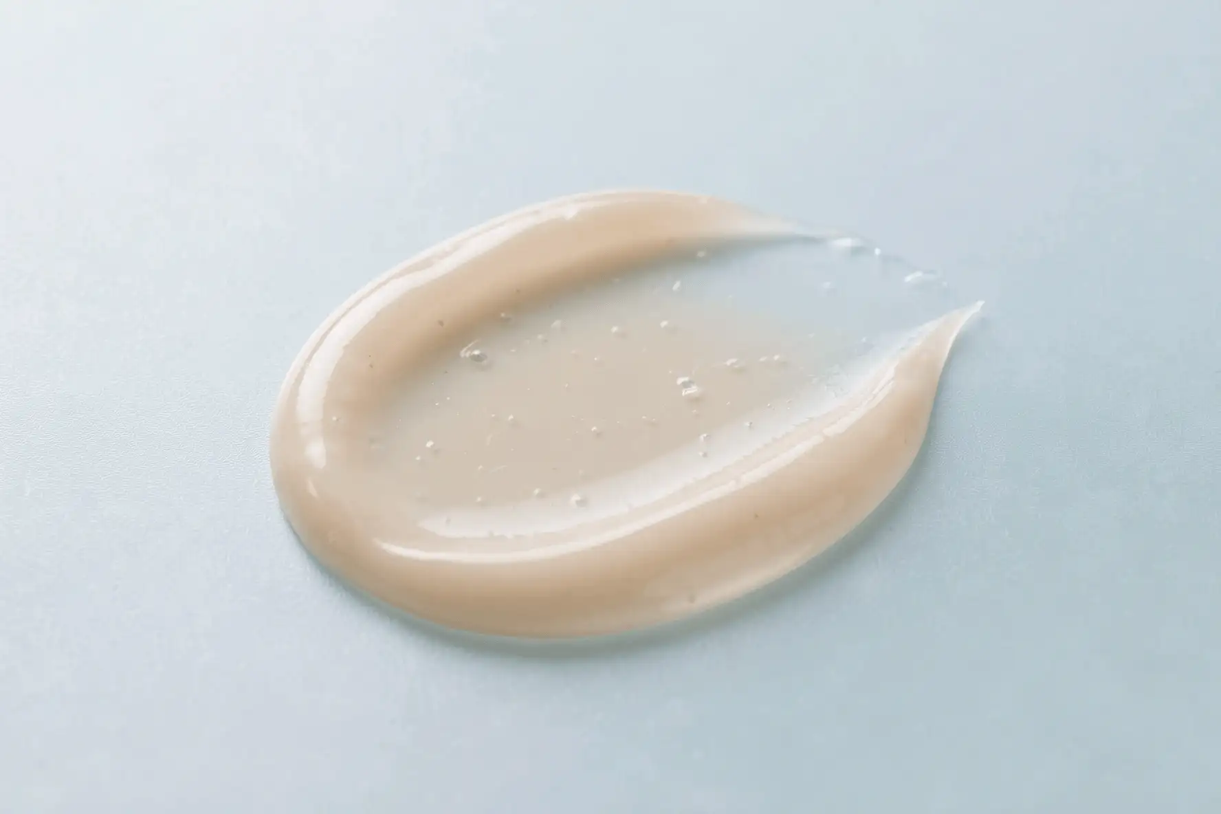 Primer plano de una textura gel-crema ligera extendida en una superficie limpia.